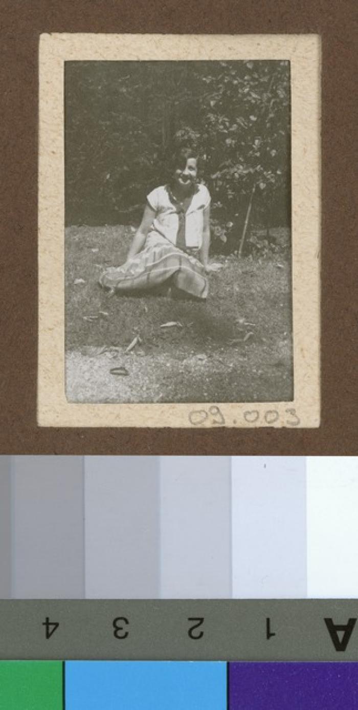Portrait d'une jeune fille assise dans un jardin.