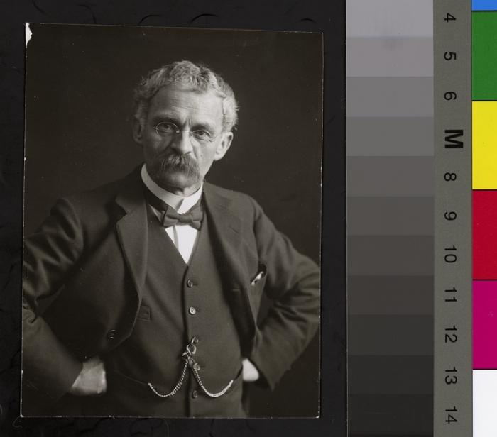 Portrait du Prof. Dr. César Roux, buste, cheveux blancs et moustache grise. Il porte des lunettes et est habillé avec un costume trois-pièces élégant. Une chaînette est accrochée à son gilet.